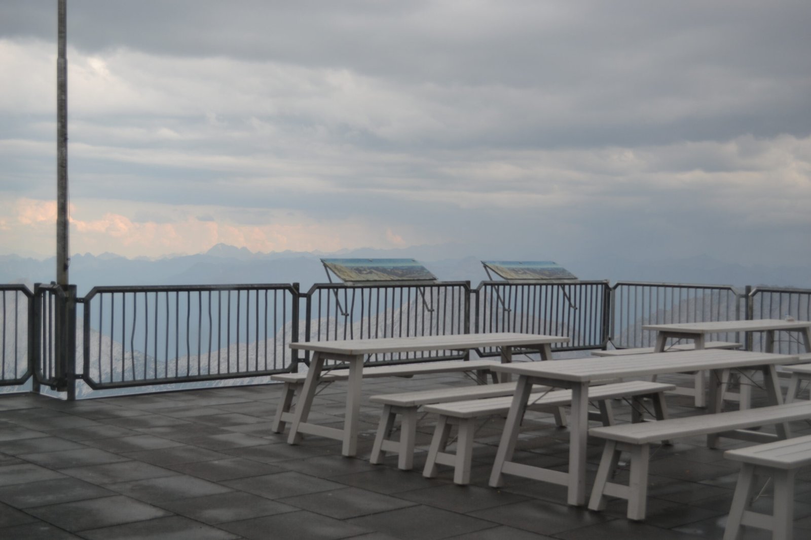 Empty picnic tables overlooking cloud-covered mountains