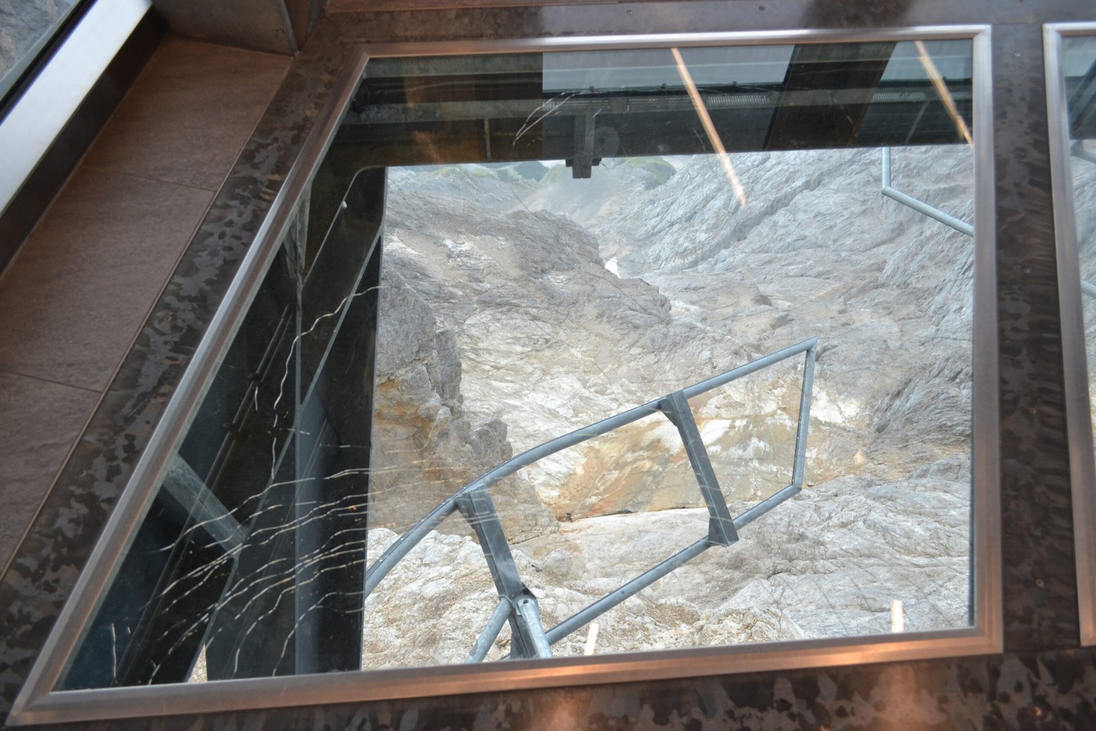 A mountain rock face and stairway seen through glass